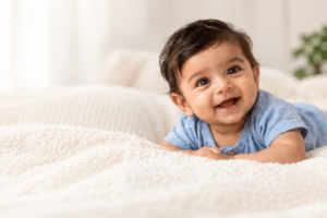 Smiling Indian baby boy on cream bedding