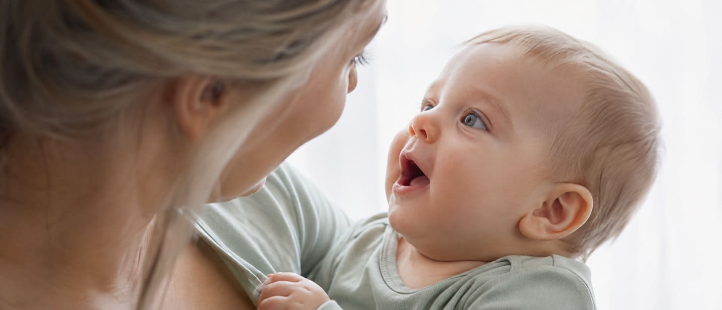 A mother talking face to face with her baby on her lap
