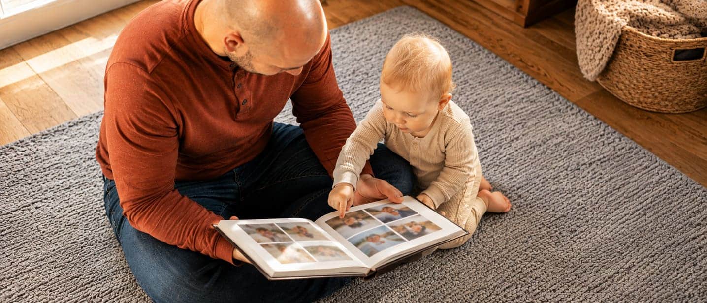 A baby pointing at a family photo while a parent names the people in it