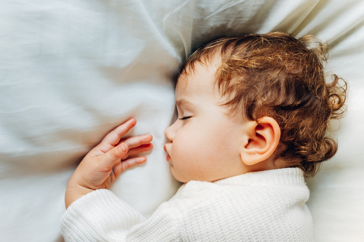 baby sleeps peacefully during a nap at noon lying on a fluffy wh