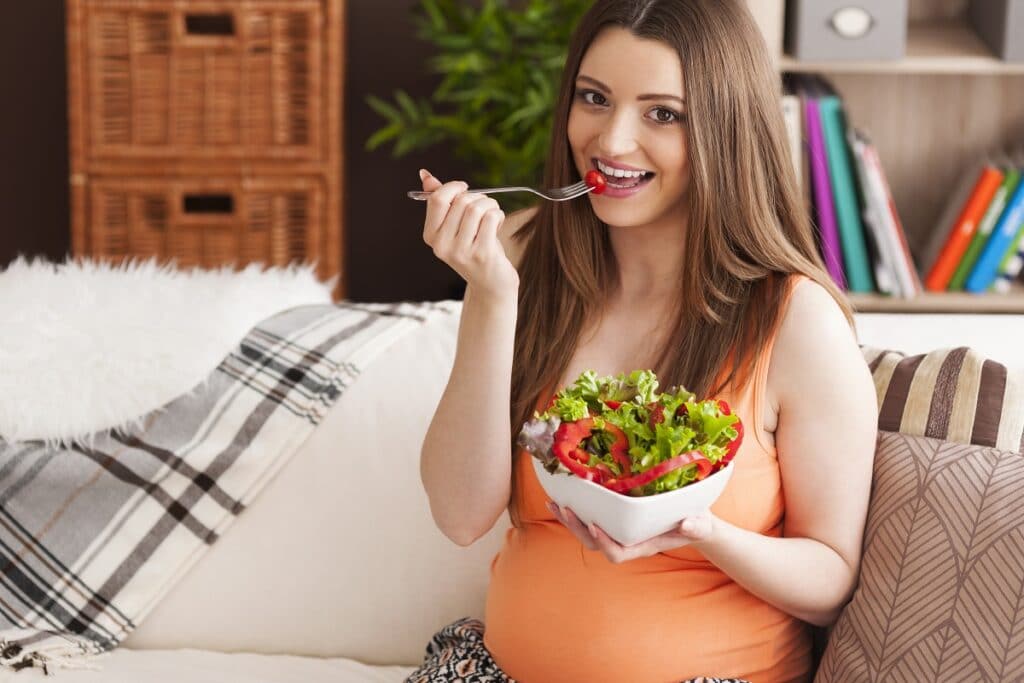 pregnant smiling woman eating salad