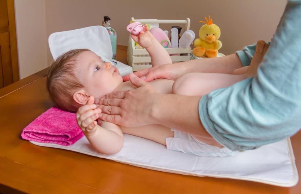 mother massaging body of her baby lying