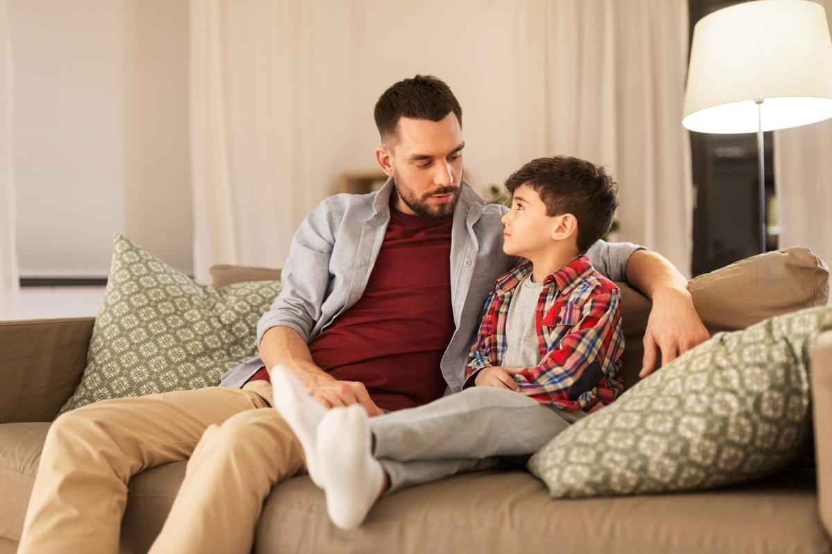 father talking to his sad little son at home