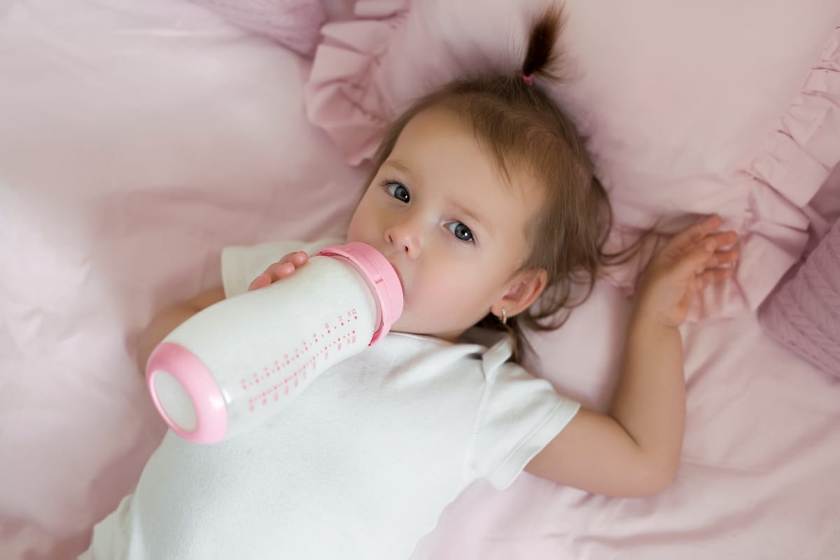 the baby is drinking milk from a bottle. healthy balanced nutrition for babies is the key to the health of the child. infant formula is full of vitamins important for baby's growth and development