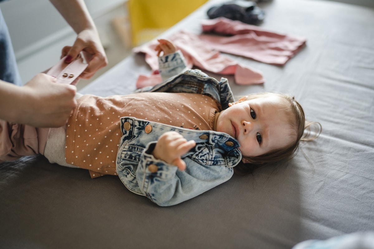 small caucasian baby girl infant child with her mother dressing