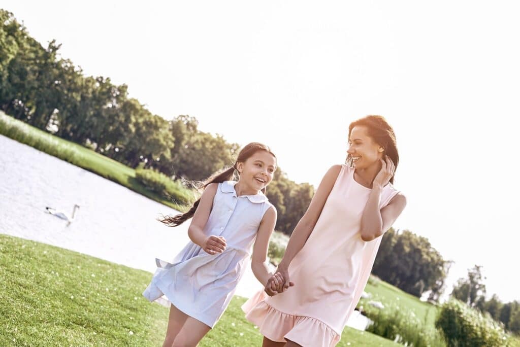 single parent, mother and daughter walking on a grassy field hol