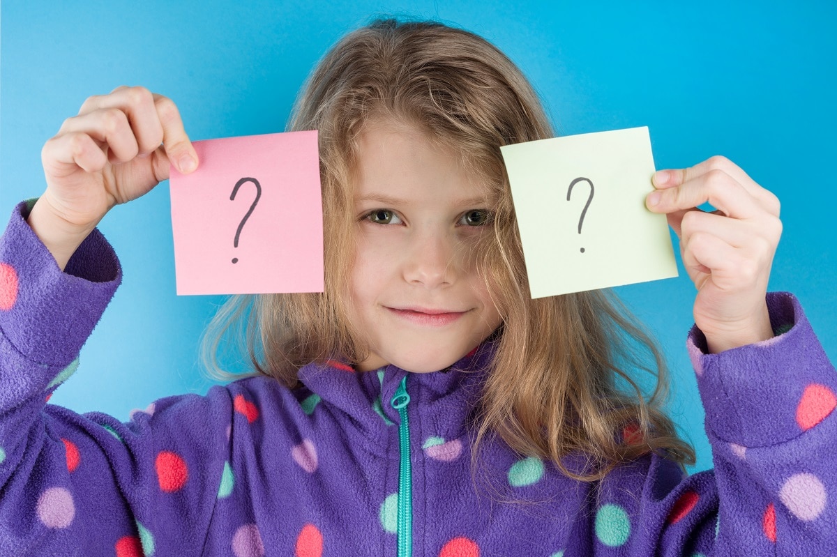 child girl holding stickers with question marks