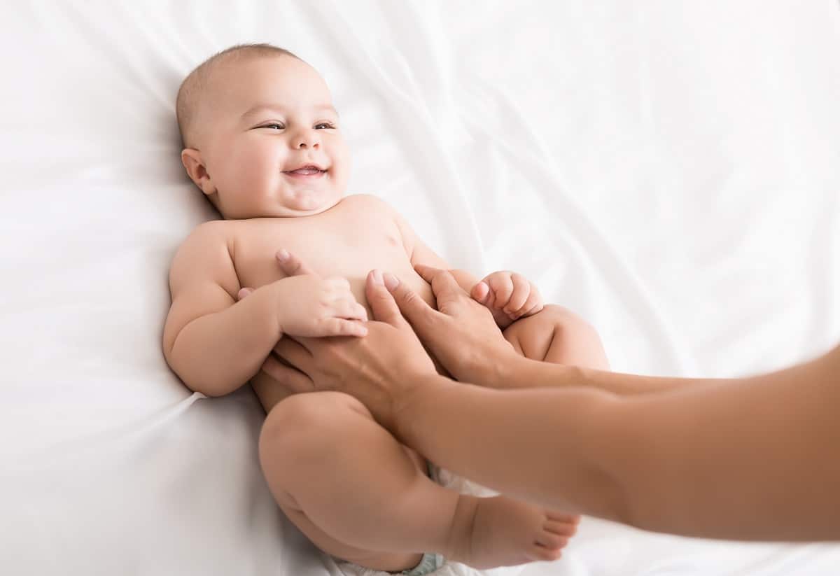 masseur massaging tummy of baby during colic