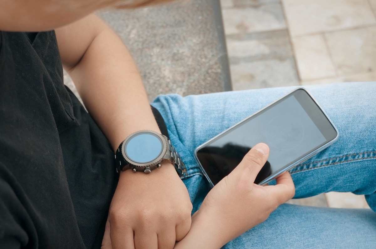 teenager connecting his samrtwatch with his smartphone