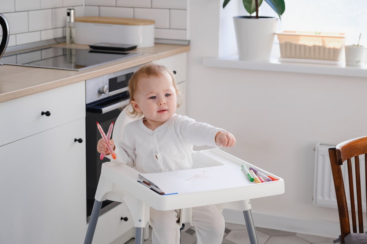 a cute baby toddler sitting on a highchair holdin 2022 03 29 22 17 53 utc