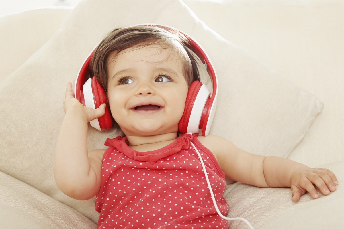 baby girl on sofa listening to red headphones