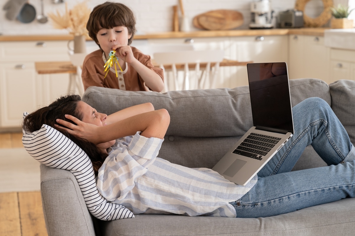 desperate young mother cover ears scream annoyed of small son bad behavior. parent work from home