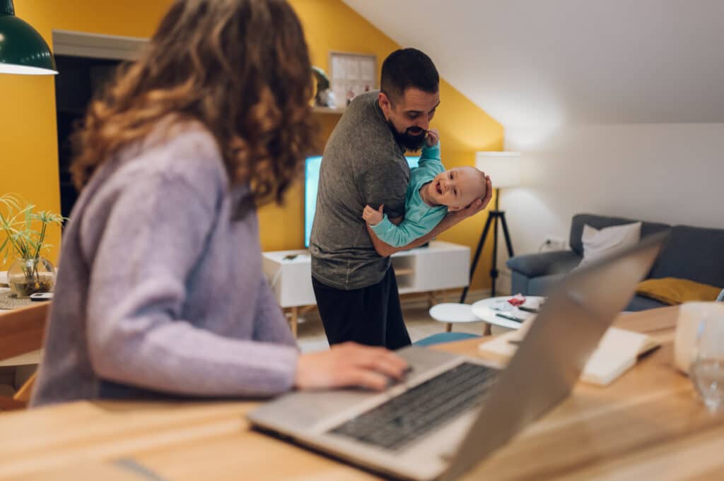 father playing with his baby boy while mom is working from home