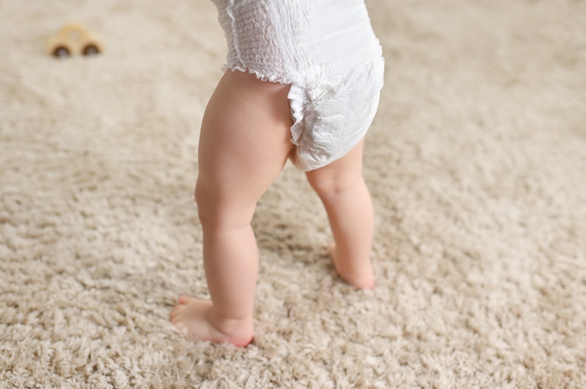 a baby in a disposable diaper on the background of a fluffy carpet.
