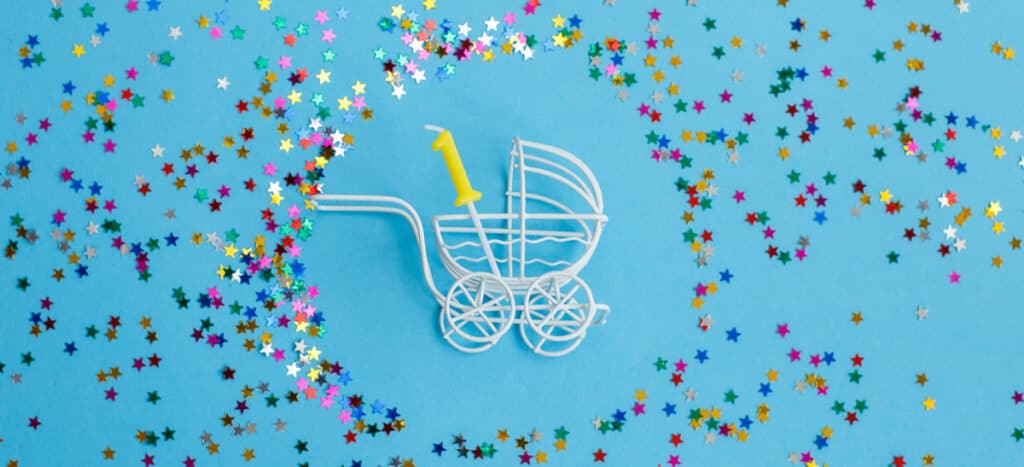 one year birthday.baby stroller with candle in form of number one on blue background with stars confetti sequins. banner