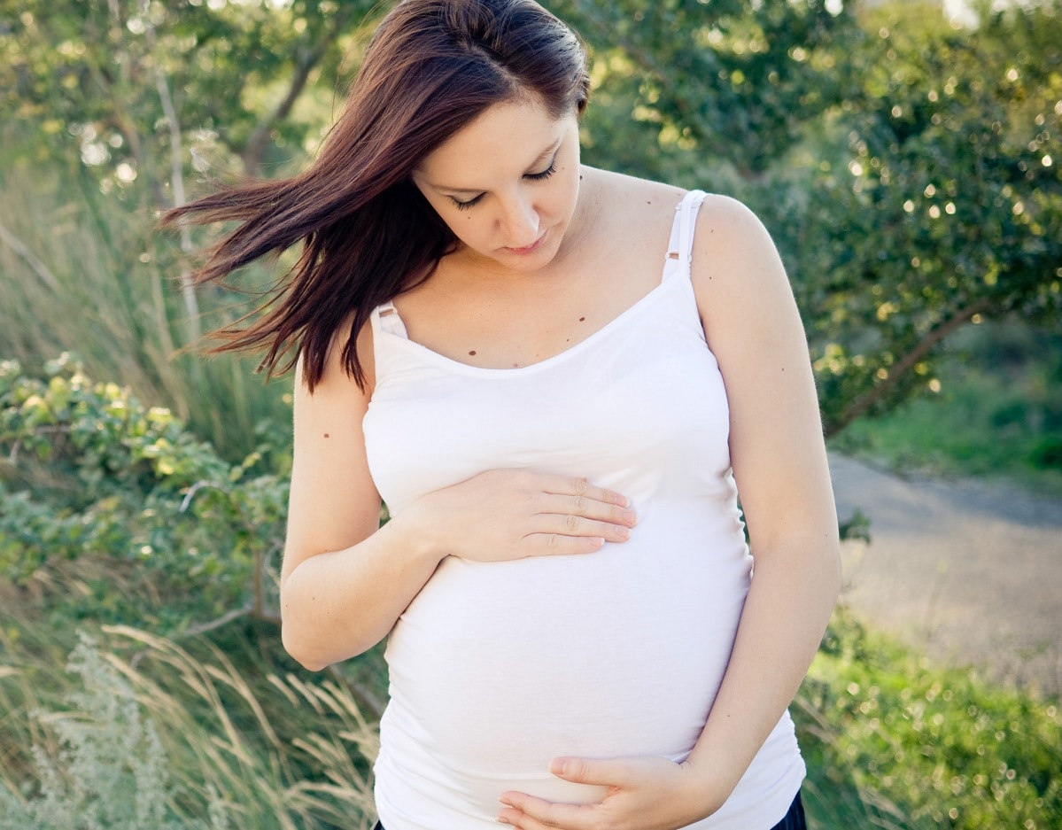 pregnant woman in nature touching her belly