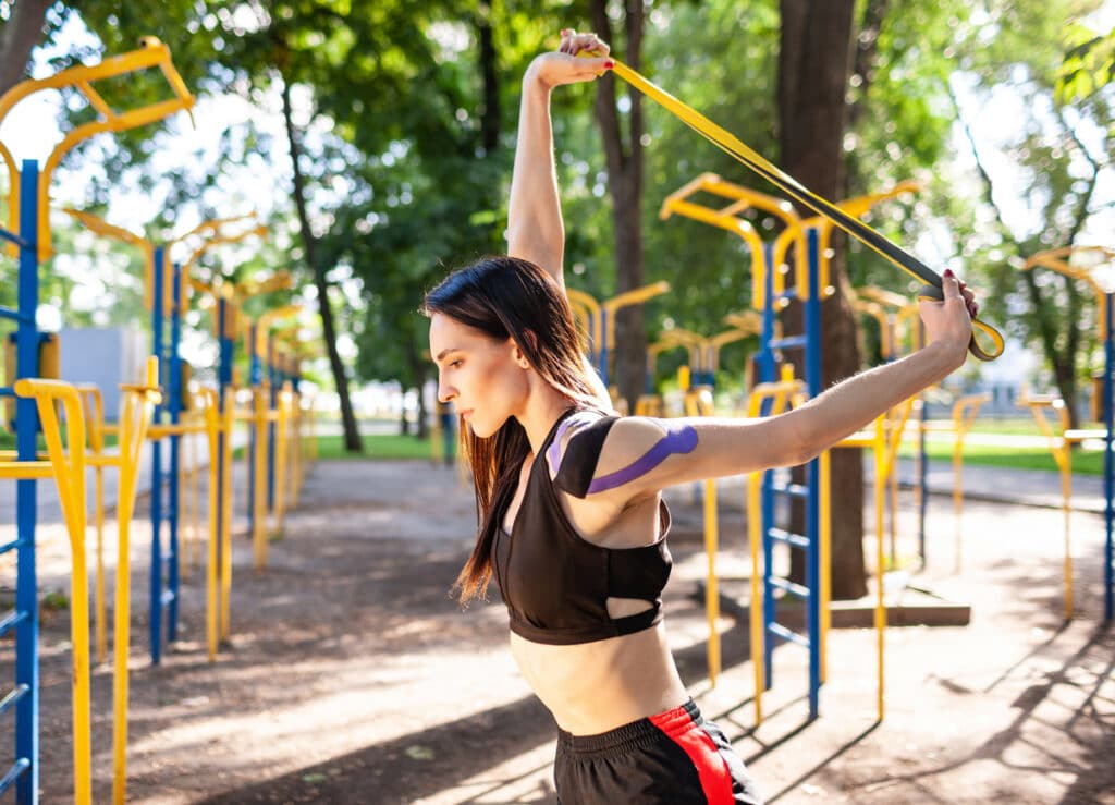 professional female athlete posing with elastic bands outdoors.