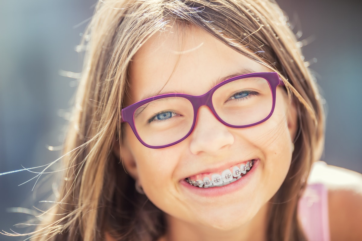 happy smiling girl with dental braces and glasses. young cute ca