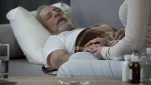 daughter caring about ill father lying on sofa, retirement and disease, health