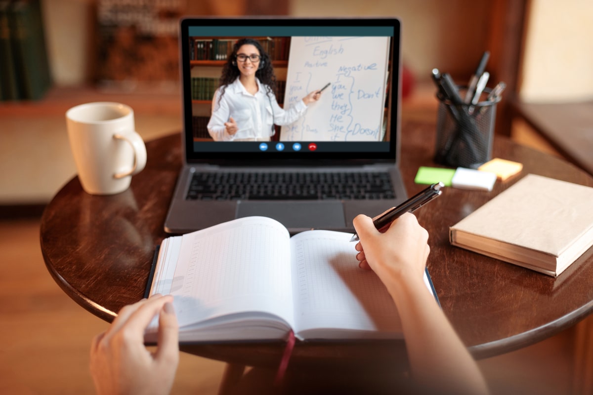 student using laptop having online class with teacher, pov