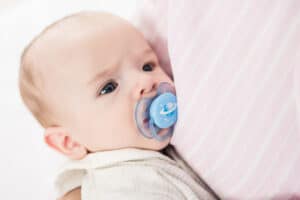 partial view of little baby with pacifier on mothers hands