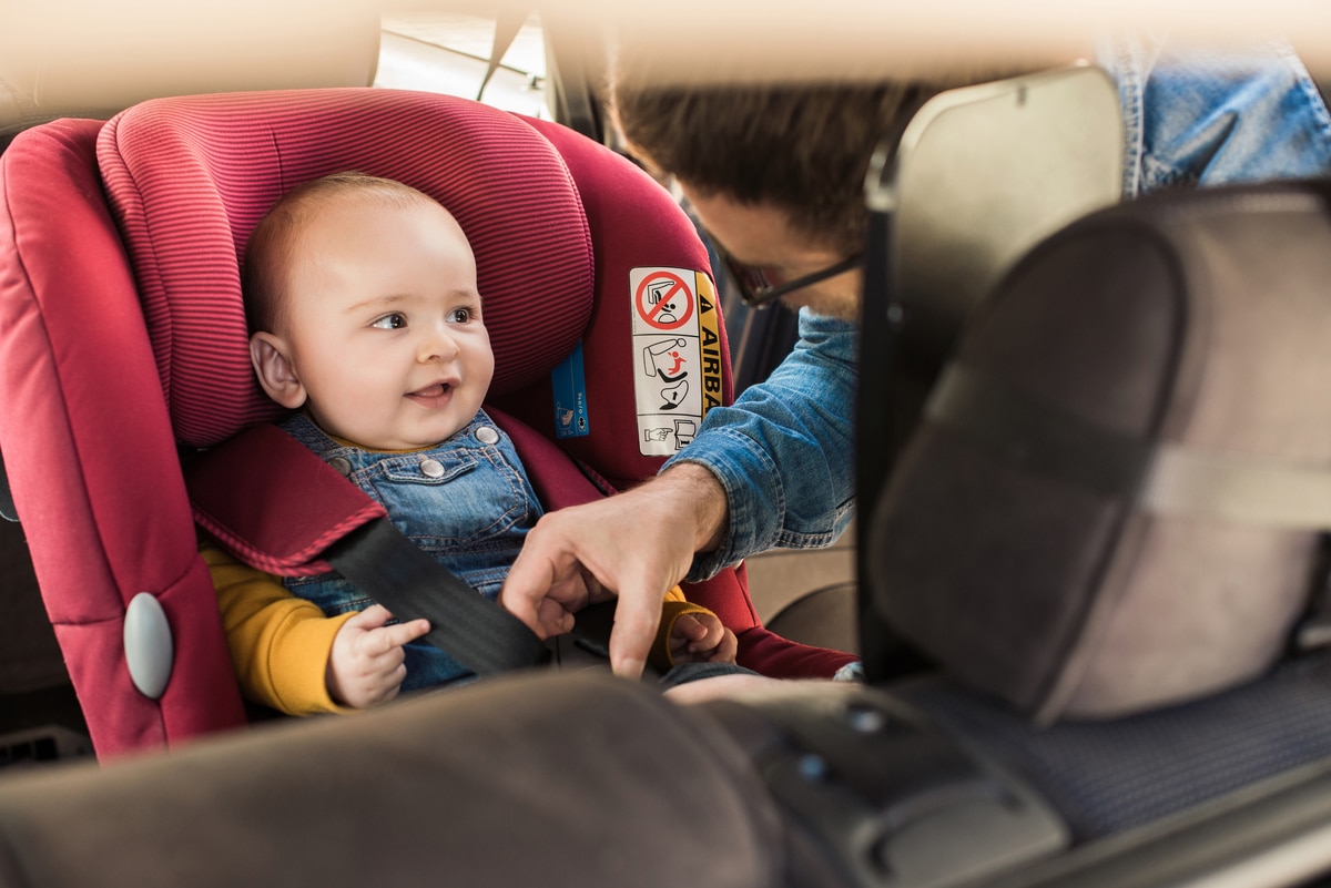 father fasten his baby in car seat