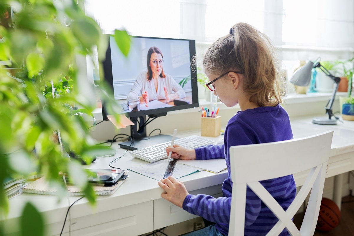 girl child studying at home using a computer for video lesson