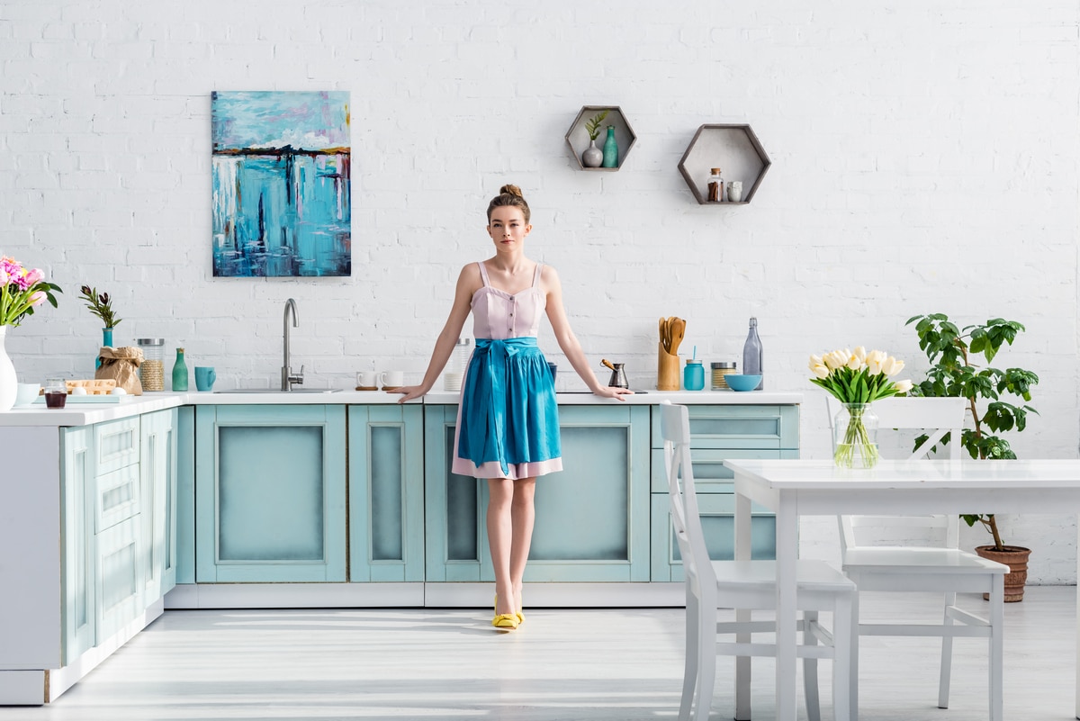 beautiful elegant young woman in apron standing in kitchen