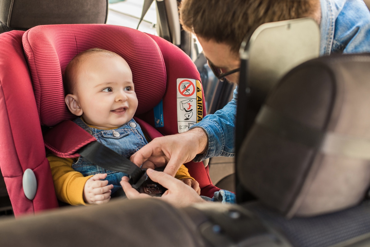 father fasten his baby in car seat