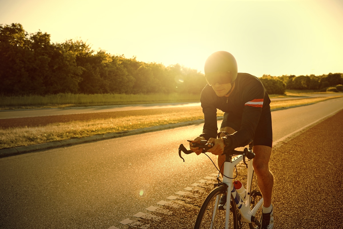 light flares from sun over man training on bike