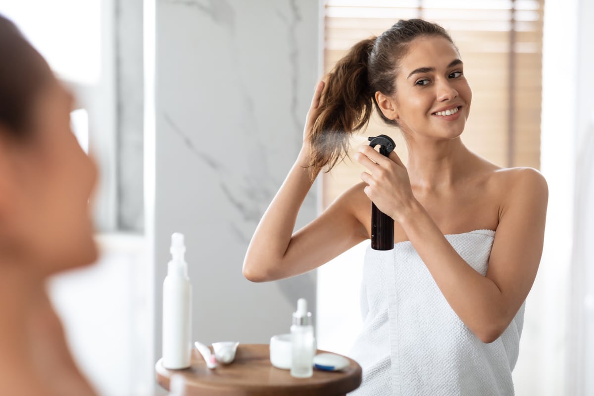 woman styling hair spraying hairspray for repair in modern bathroom