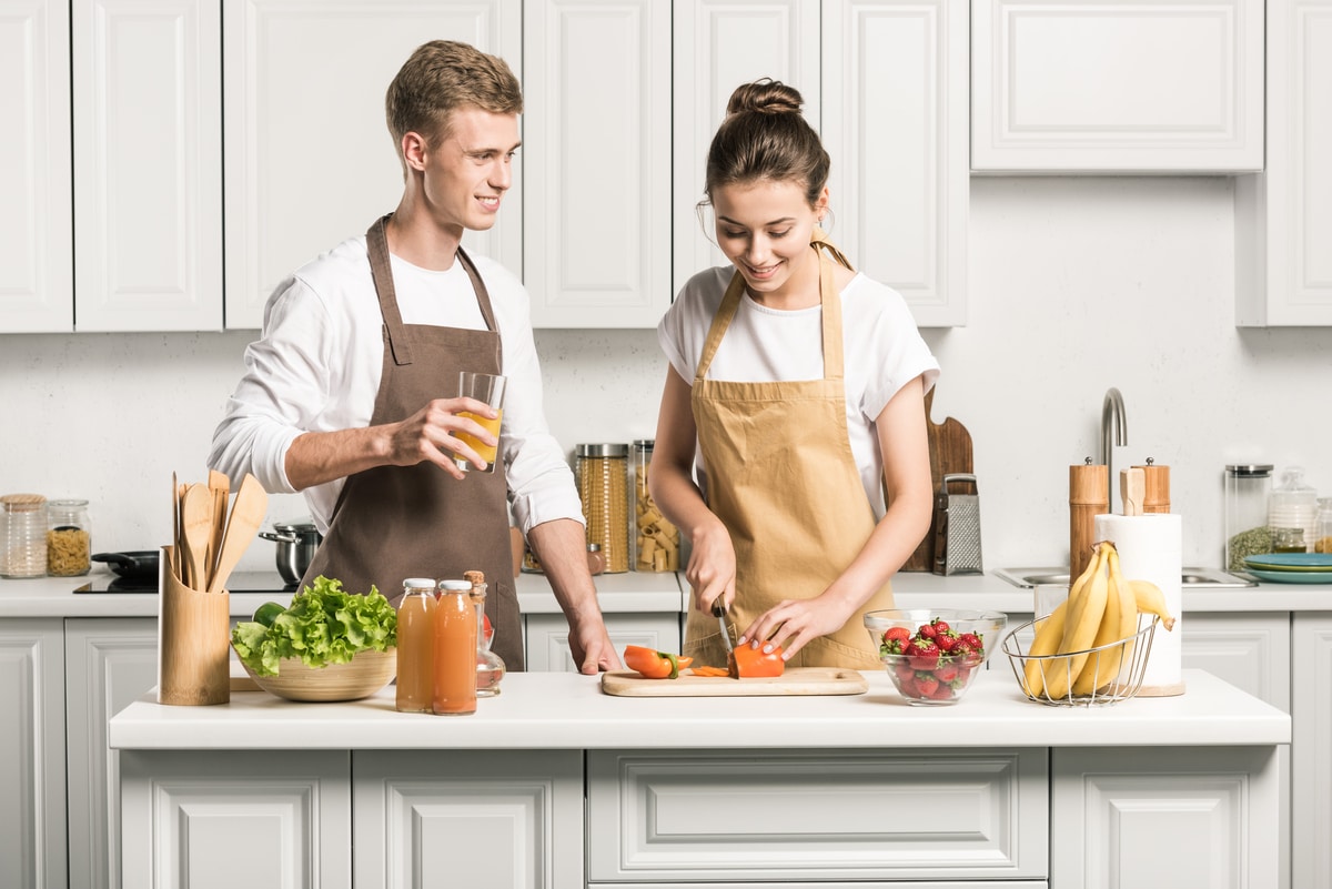 young couple cooking salad and cutting vegetables in kitchen