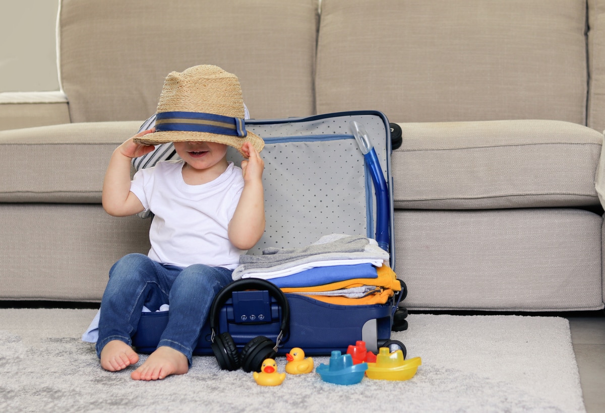 cute funny little baby boy siiting in blue suitcase with hat on