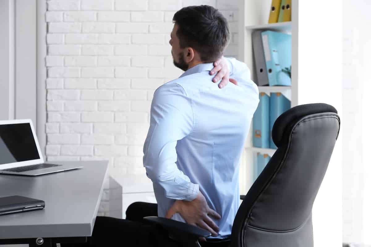 posture concept. man suffering from back pain while working with