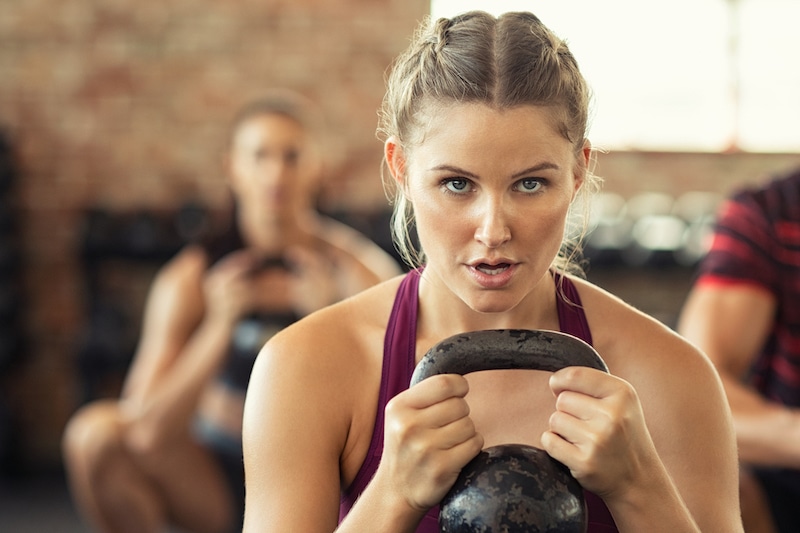 determined fitness woman doing squat with kettle bell