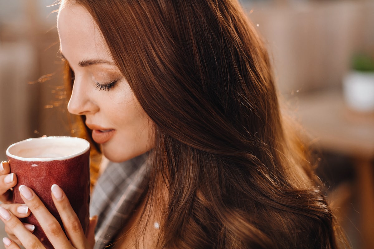 a girl drinks coffee in a coffee shop, beautiful hair of a girl