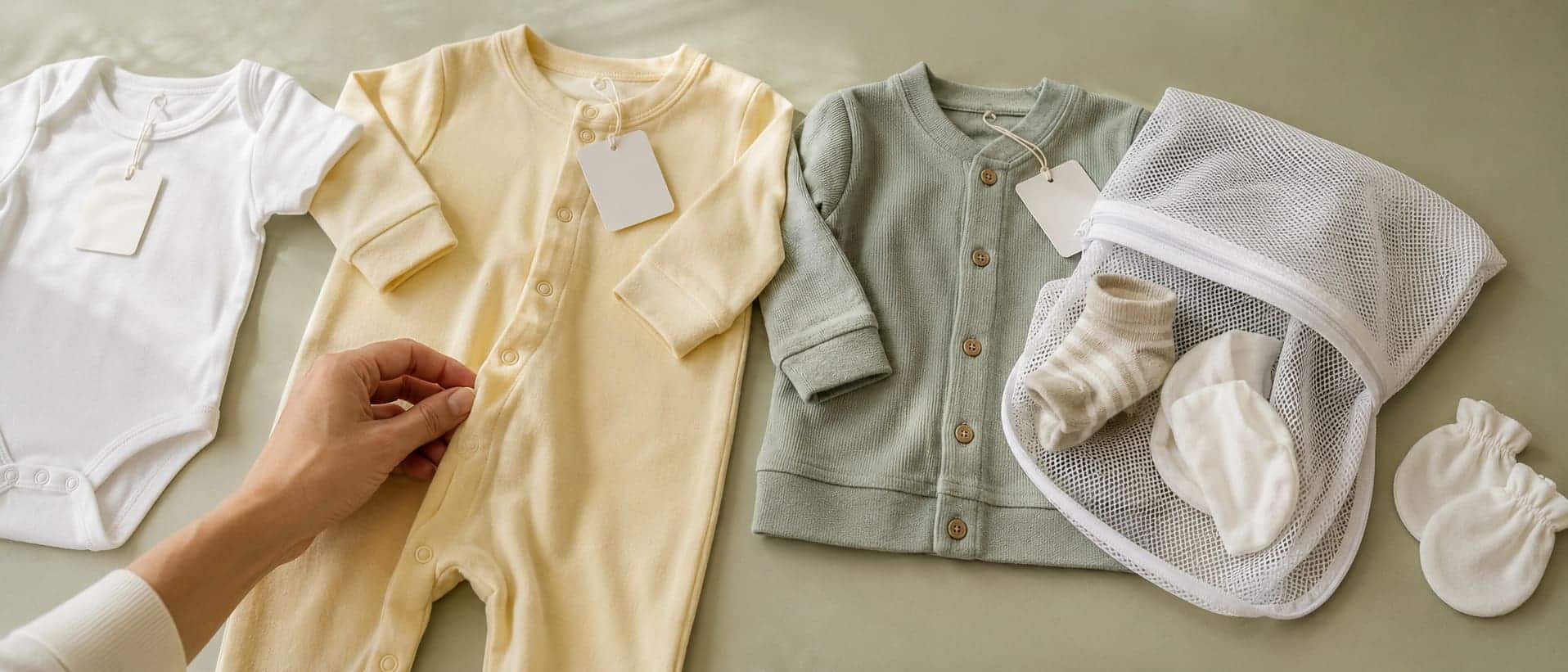 New baby clothes sorted beside a mesh laundry bag before the first wash