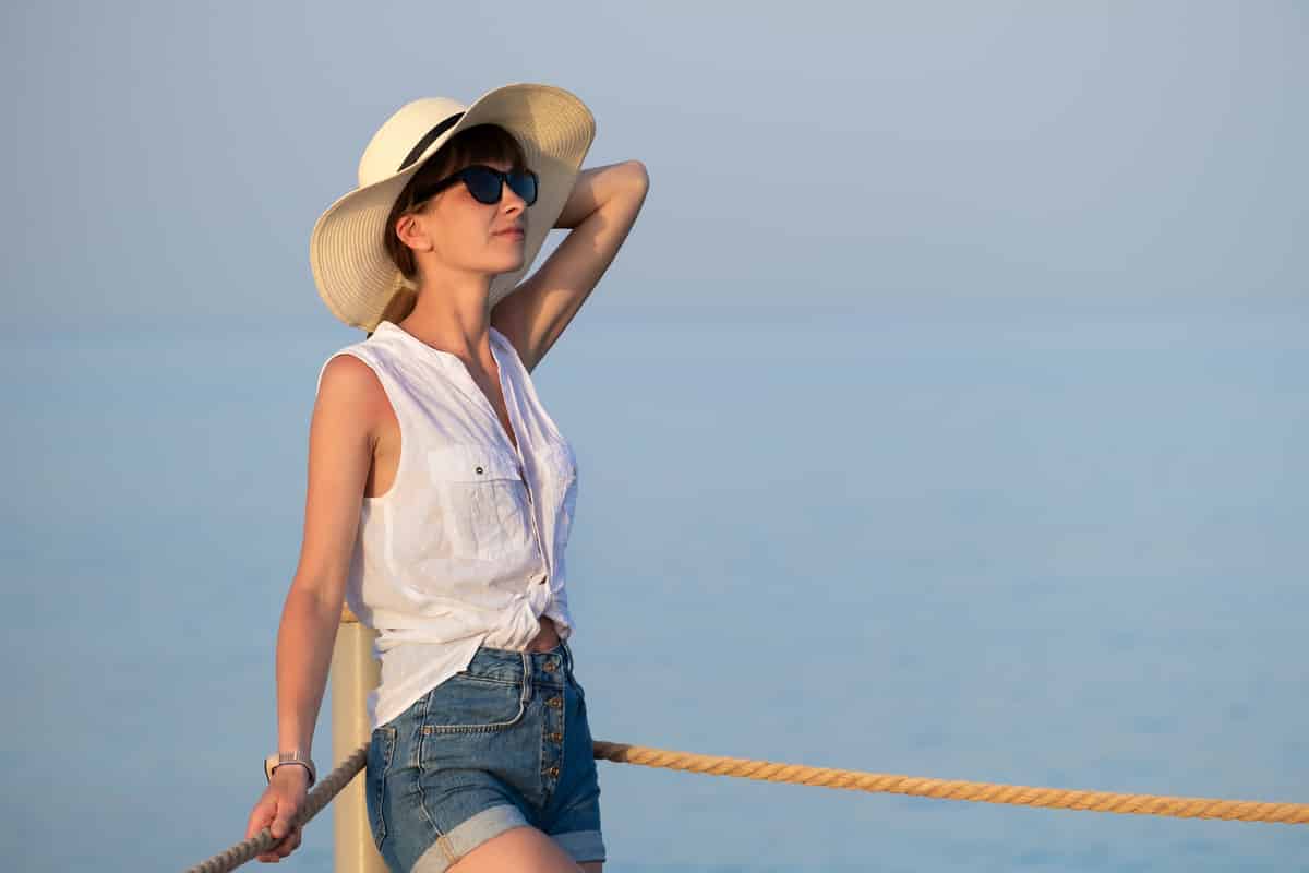 young woman in casual outfit relaxing on seaside on warm summer day.