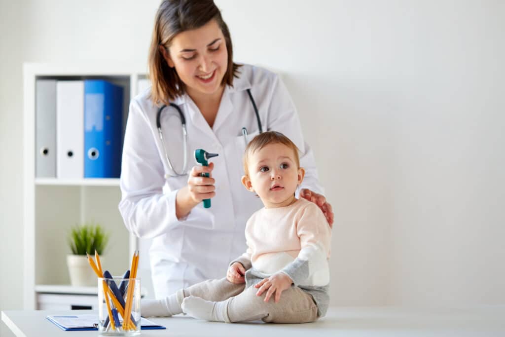 doctor with baby and otoscope at clinic