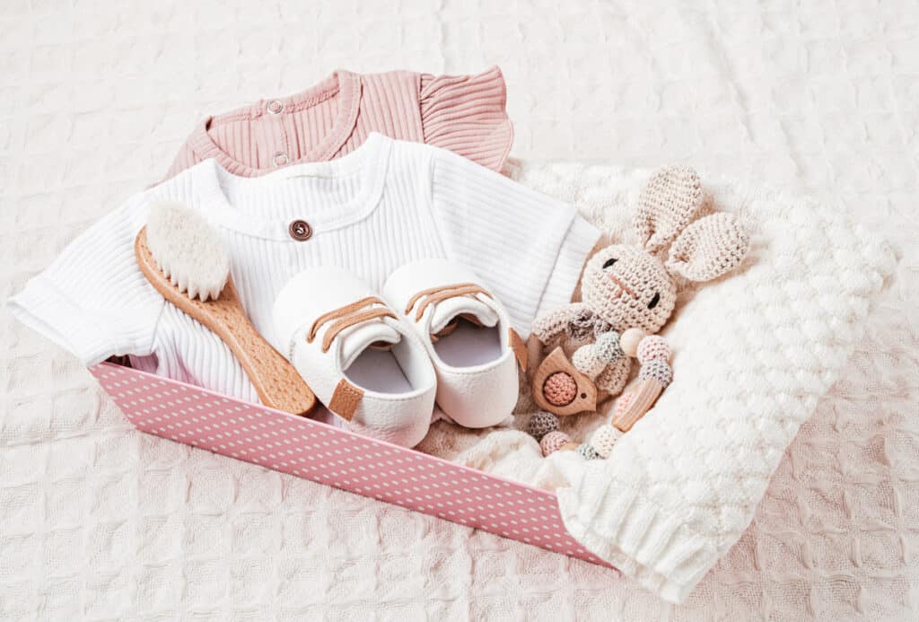 gift basket with gender neutral baby garment and accessories. care box of organic newborn cotton clothes