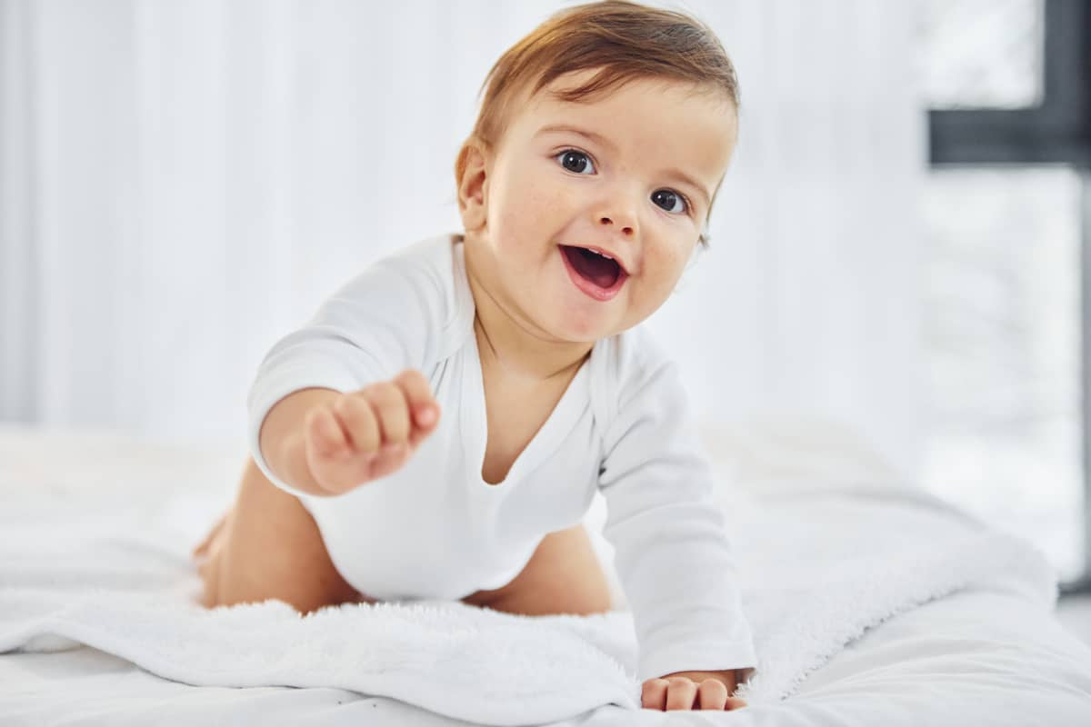 playing on the bed. cute little baby is indoors in the domestic room