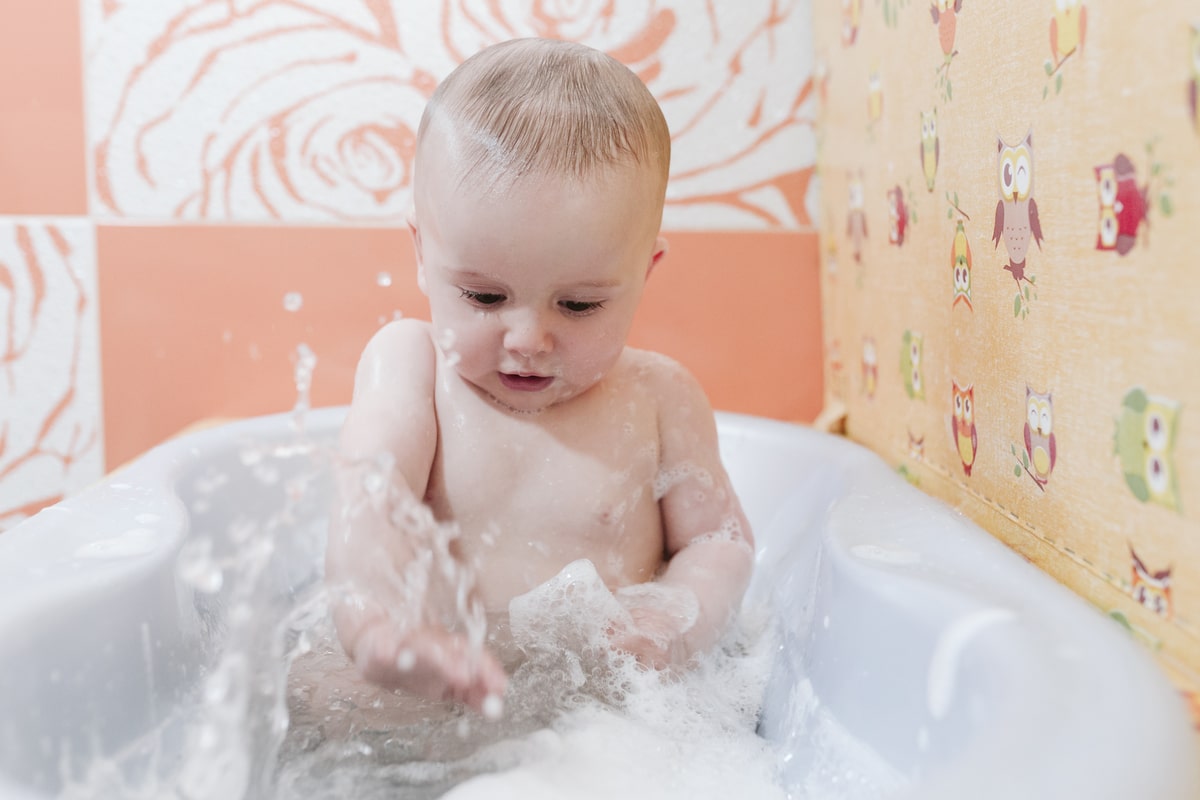 portrait of a baby in bathtub at home splashing water