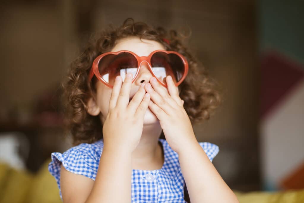 portrait of pretty baby girl with dark curly hair in sunglasses