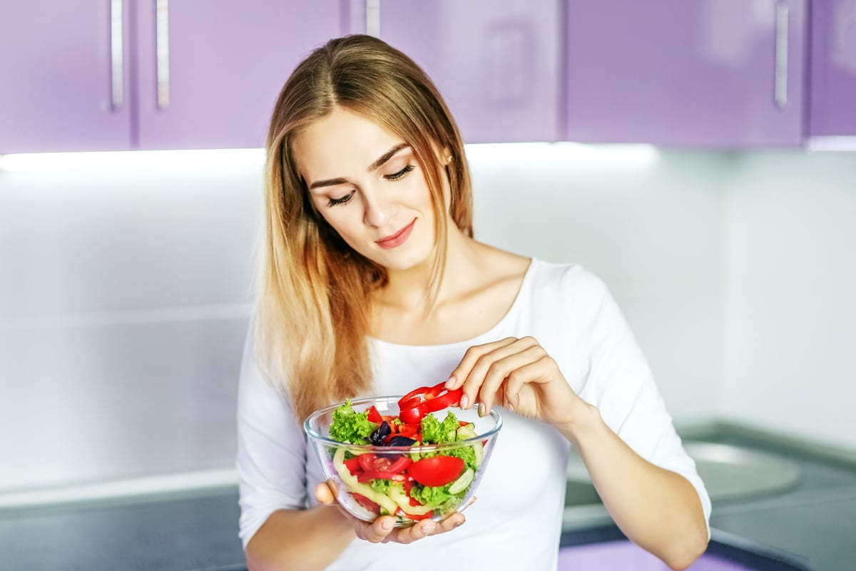 young happy girl eating vegetable spring salad. the concept is