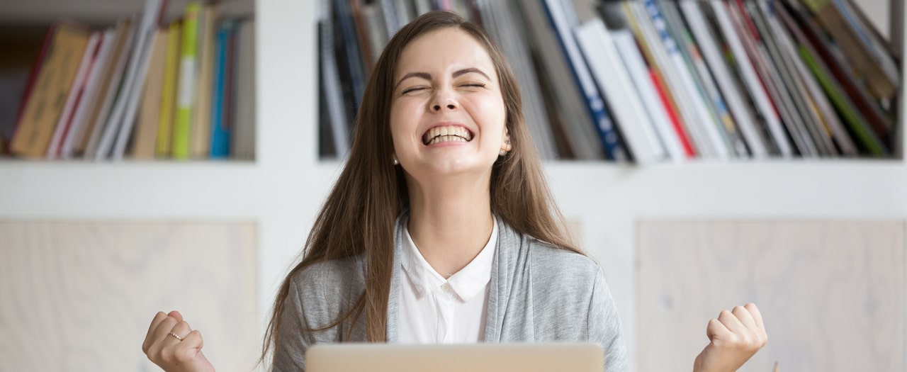 happy woman sitting at workplace celebrating great opportunity at work