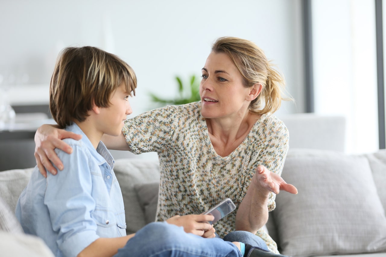 mother giving warning to young boy using smartphone