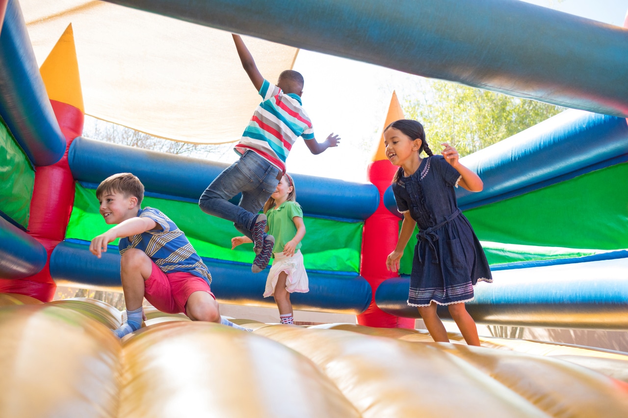 friends jumping on bouncy castle at playground