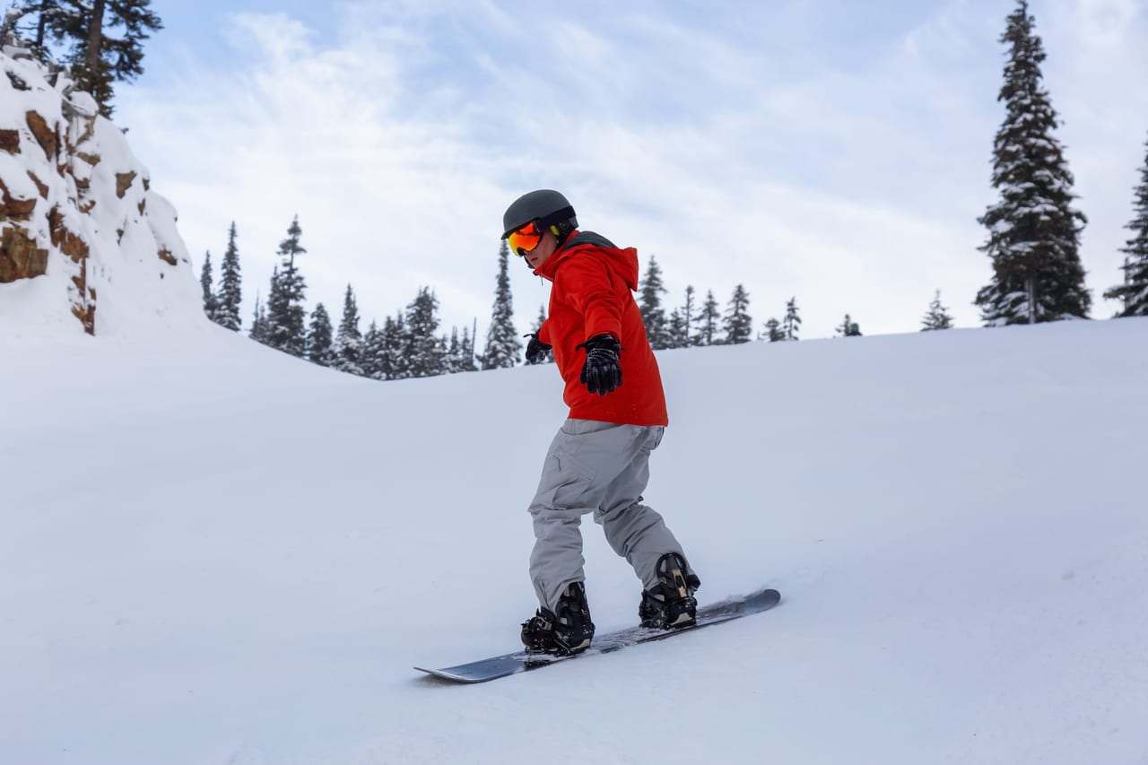 male snowboarder is riding down a ski run