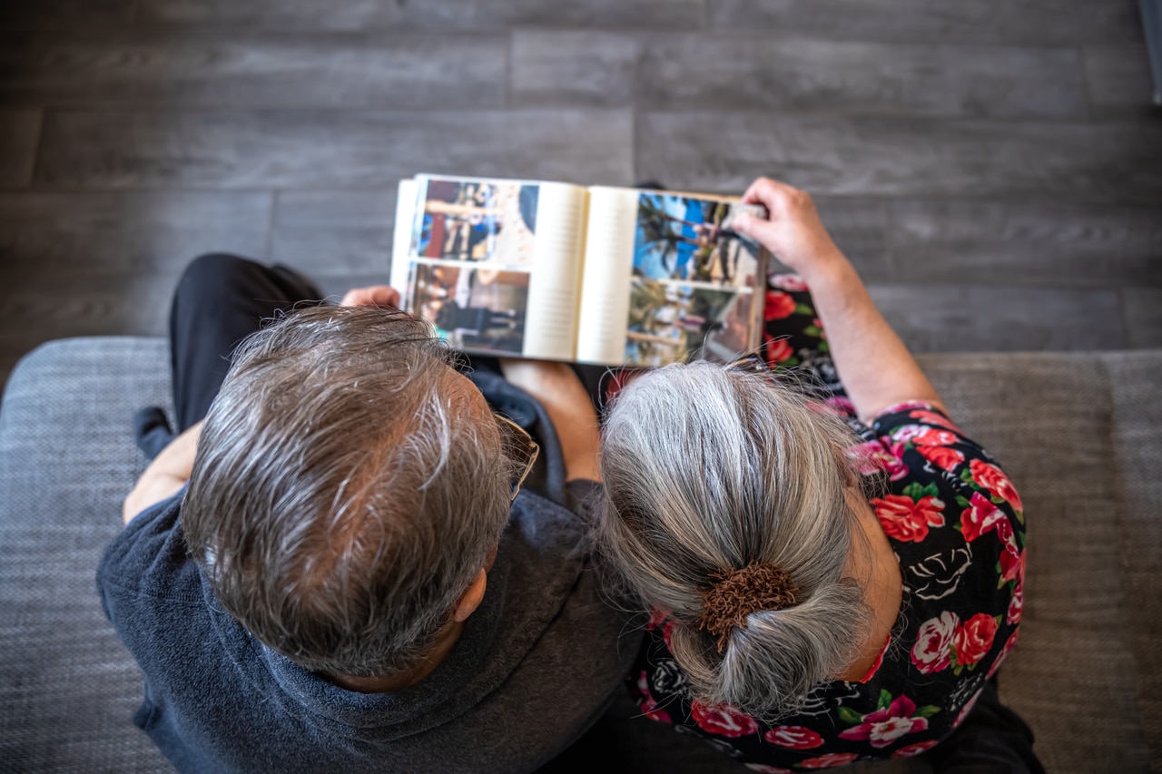 an elderly man and woman are looking at family photo albums.