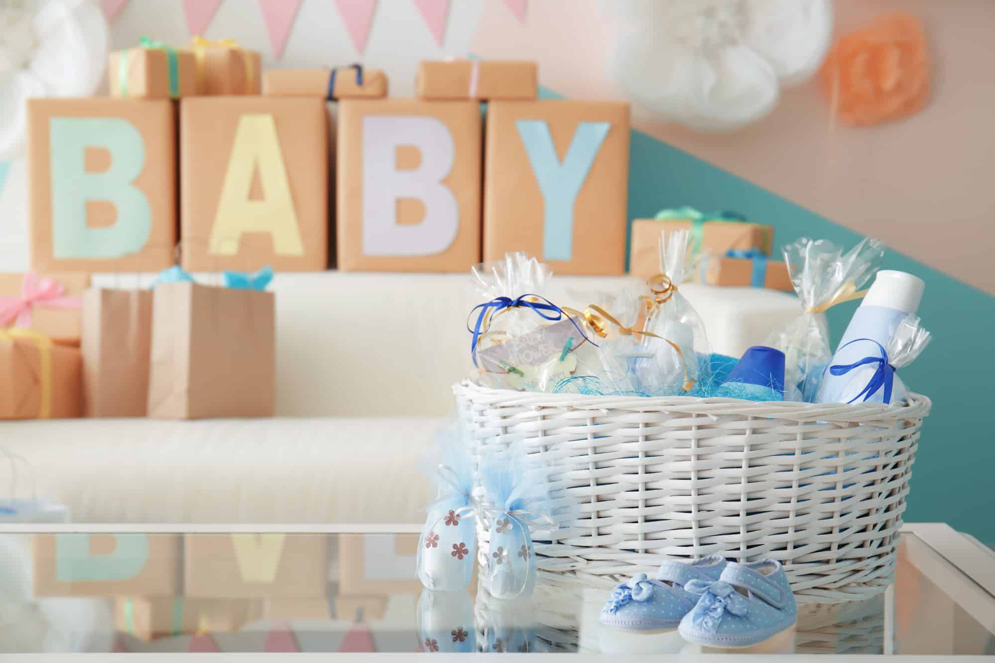 wicker basket with gifts for baby shower party on table indoors